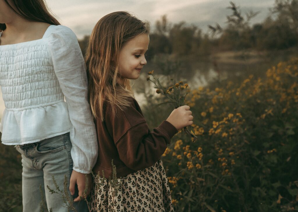 Little girl smelling yellow flowers she picked during lifestyle session with a Cincinnati photographer