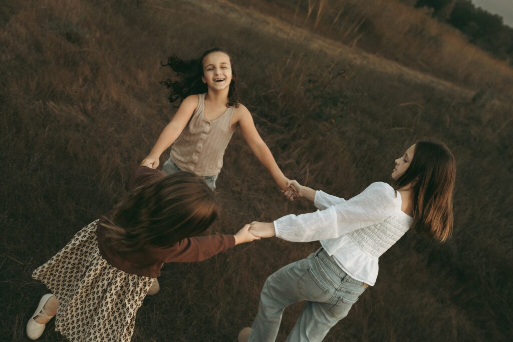 Sisters playing ring around the rosie during a Cincinnati lifestyle family session in a field