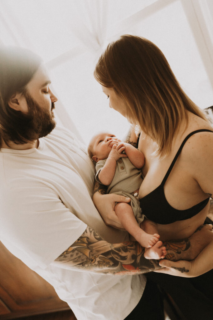 family admiring newborn baby in nursery