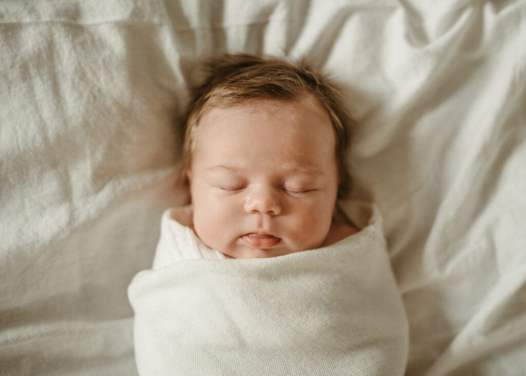 baby girl sleeping in a white swaddle