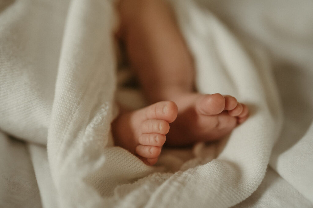 close up detail shot of newborn toes in a white blanket