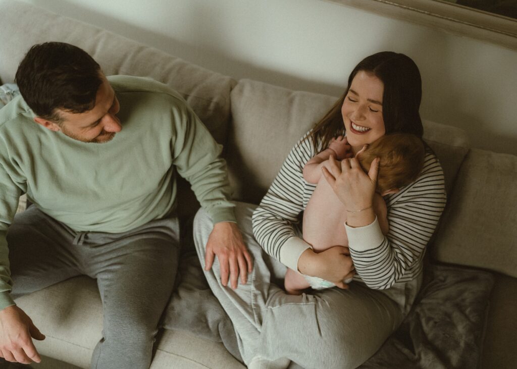Cincinnati family laughing on their couch during their in home session with a lifestyle photographer.
