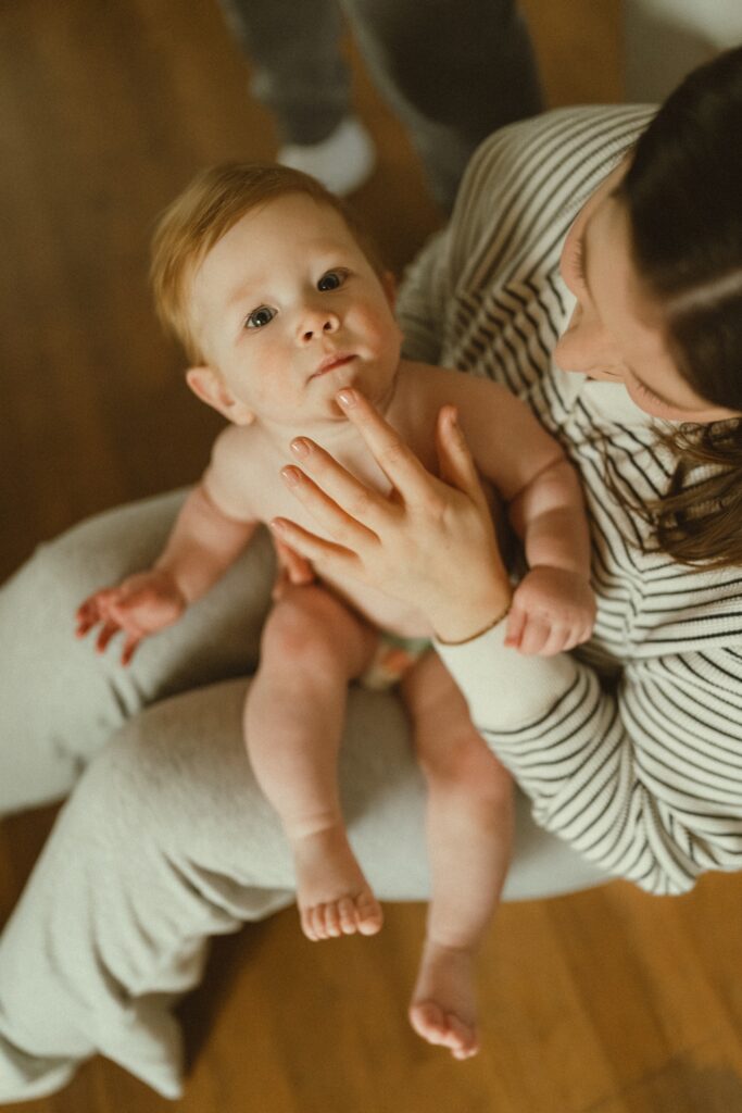 Toddler boy sitting on mom's lap while she plays with his lip