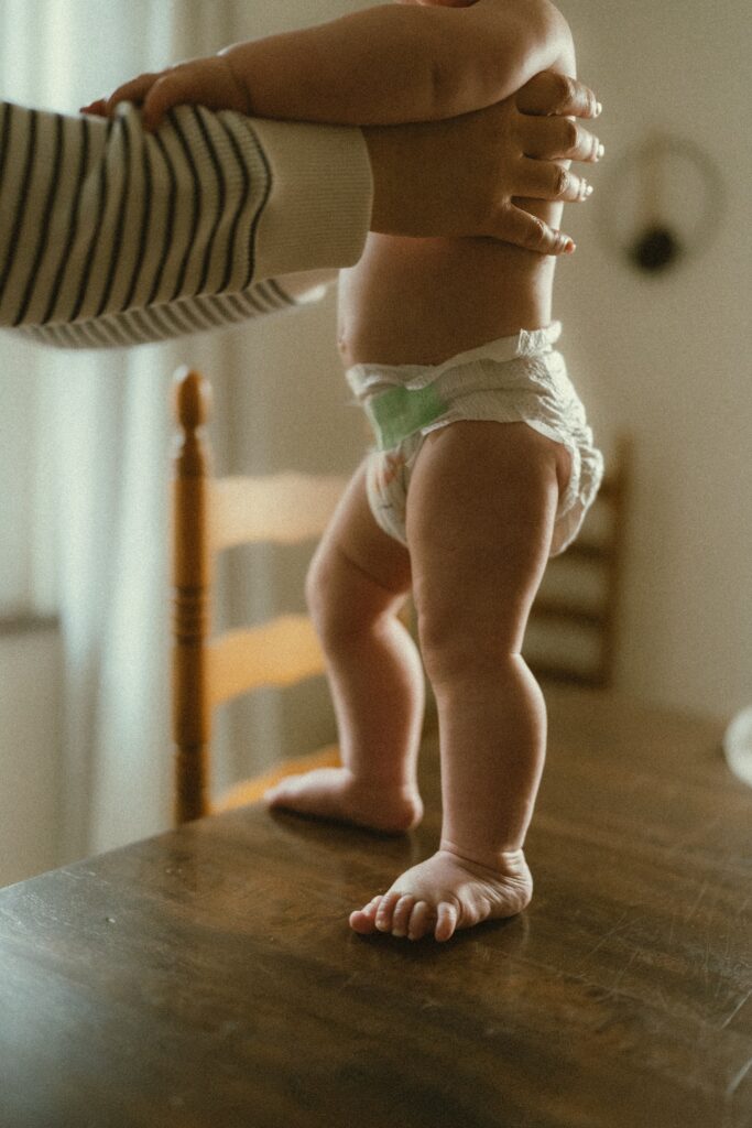 Close up photo of a toddler standing on the dining room table during a lifestyle session with a cincinnati family photographer in their home.