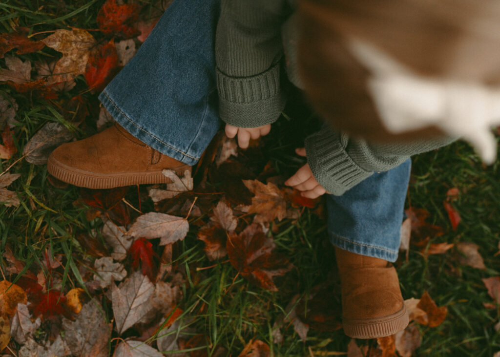 toddler playing with fall leaves