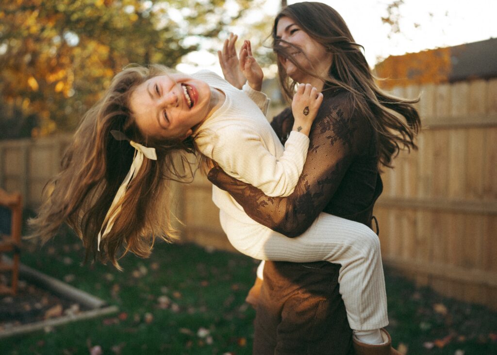 mom swinging daughter around while daughter is laughing wearing a white set during their lifestyle family session with a cincinnati photographer
