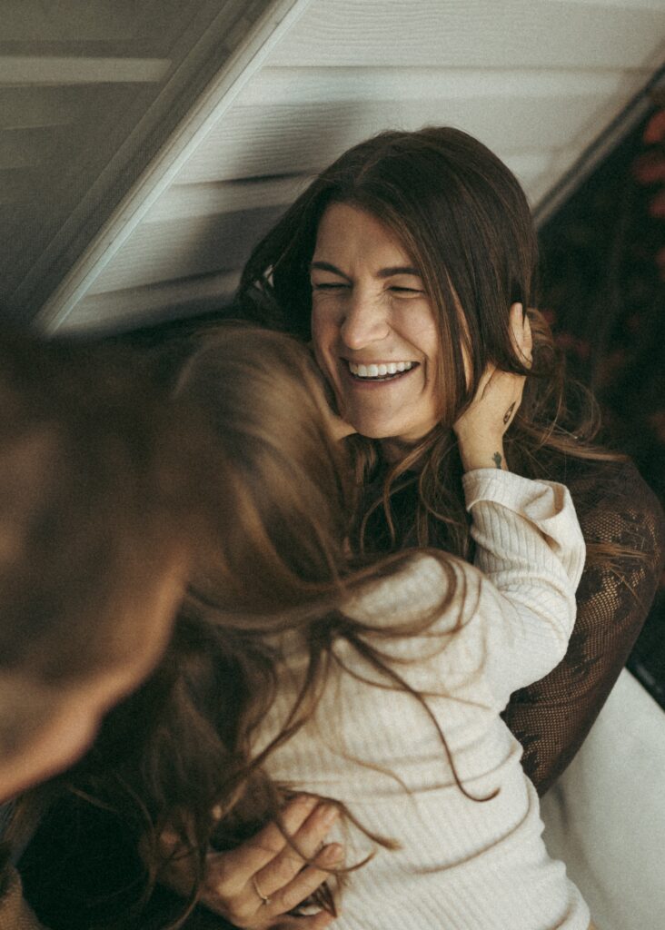 A daughter holding her mom's face while laughing during their connection based cincinnati lifestyle photography session