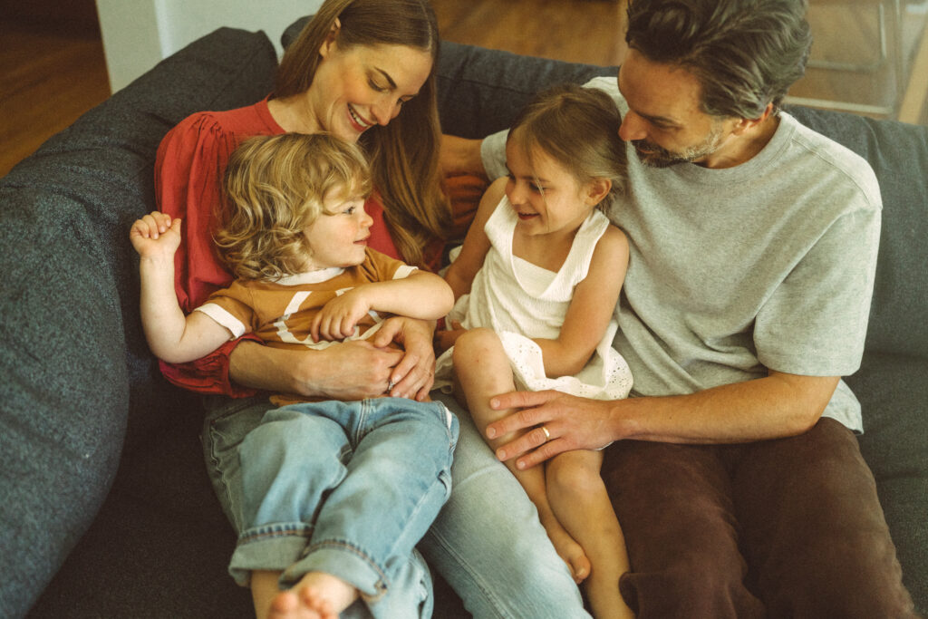 family of four cuddling on their couch and looking at each other in their cincinnati home