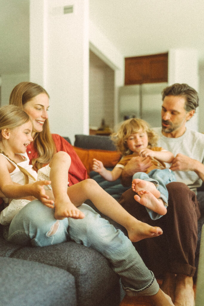 young family with two toddlers tickling on their couch with a cincinnati lifestyle photographer