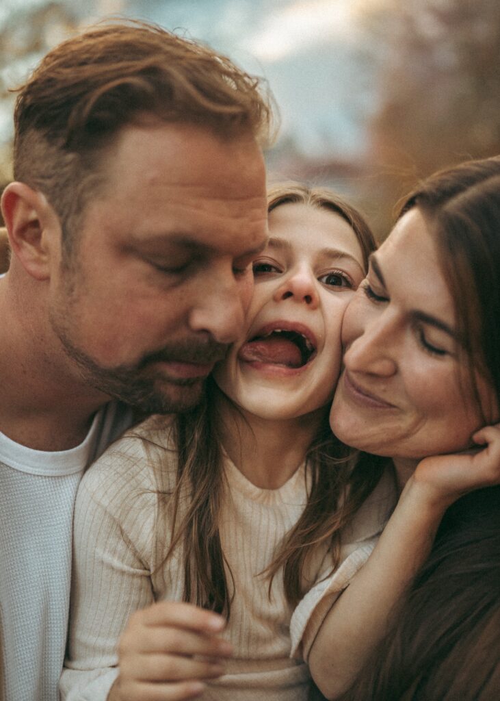 Dad, daughter, and mom squishing their faces together showing their silly connection during their photo session.