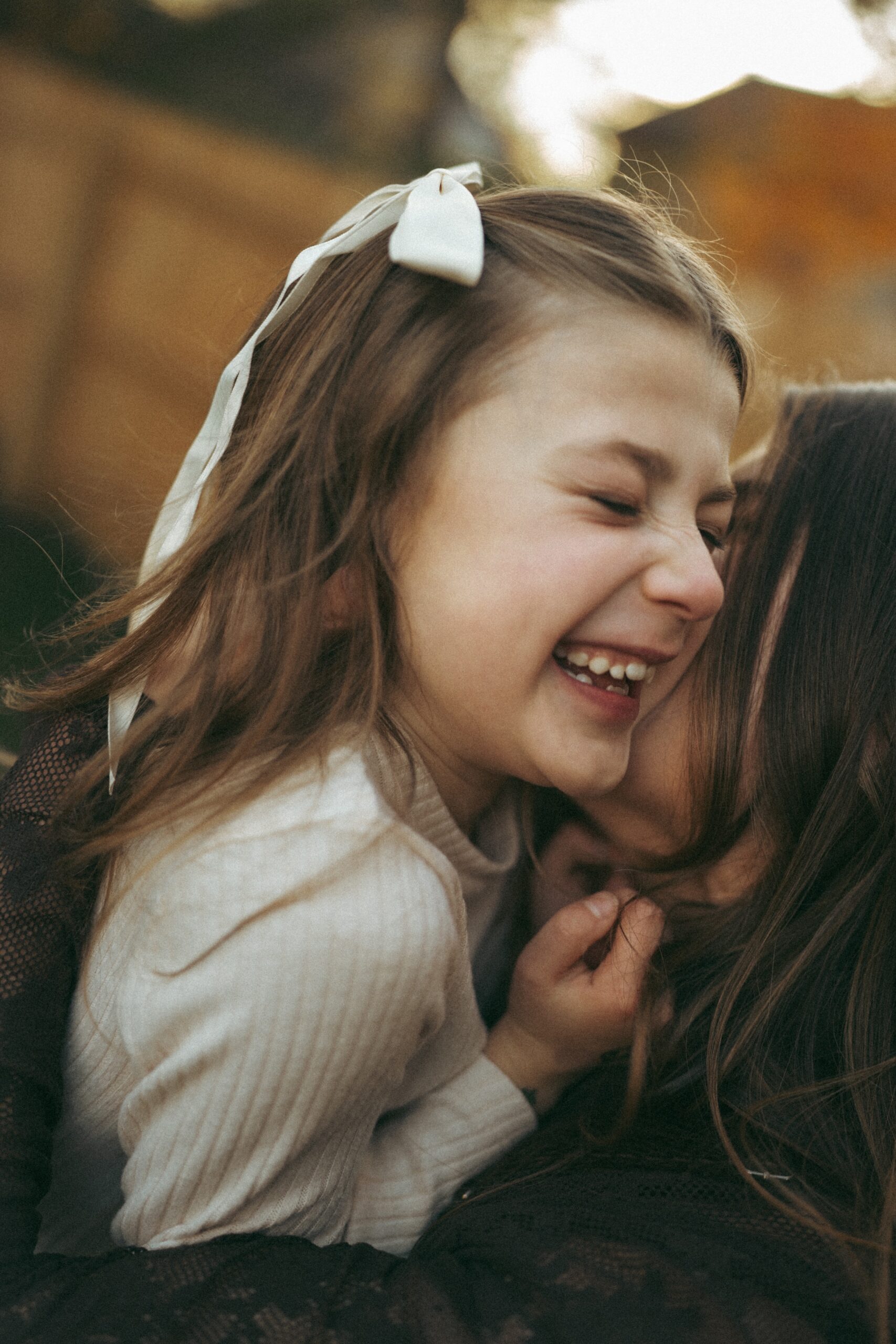 closeup shot of little girl laughing with her eyes closed while mom kisses her cheek during their photography session in cincinnati