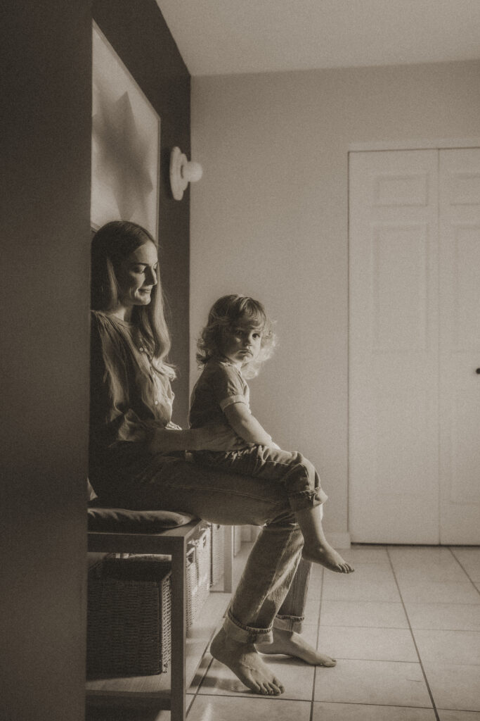 Black and white image of toddler boy sitting on mom's lap in their cincinnati home