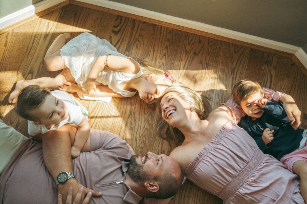 Cincinnati lifestyle photographer has family lay on their wood floor during their session to capture light and shadows as they snuggle together