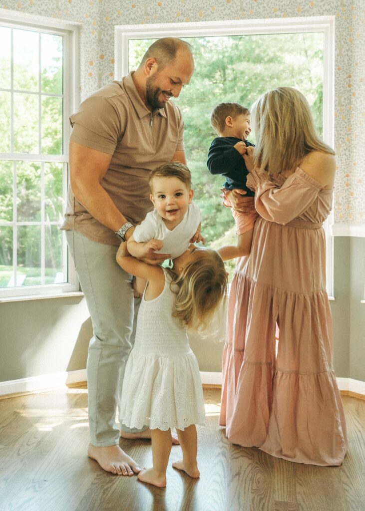 Cincinnati lifestyle photographer captures mom, dad, and three children playing in their kitchen near the window