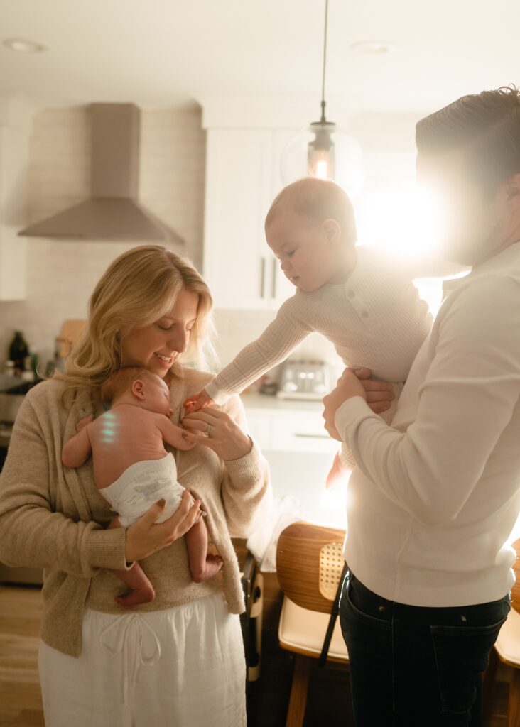 toddler brother reaching for his newborn sister