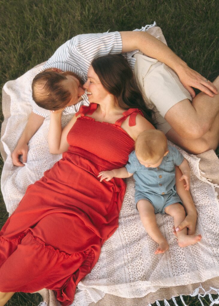family snuggling on a blanket with mom wearing a red dress during their family lifestyle photography session in cincinnati