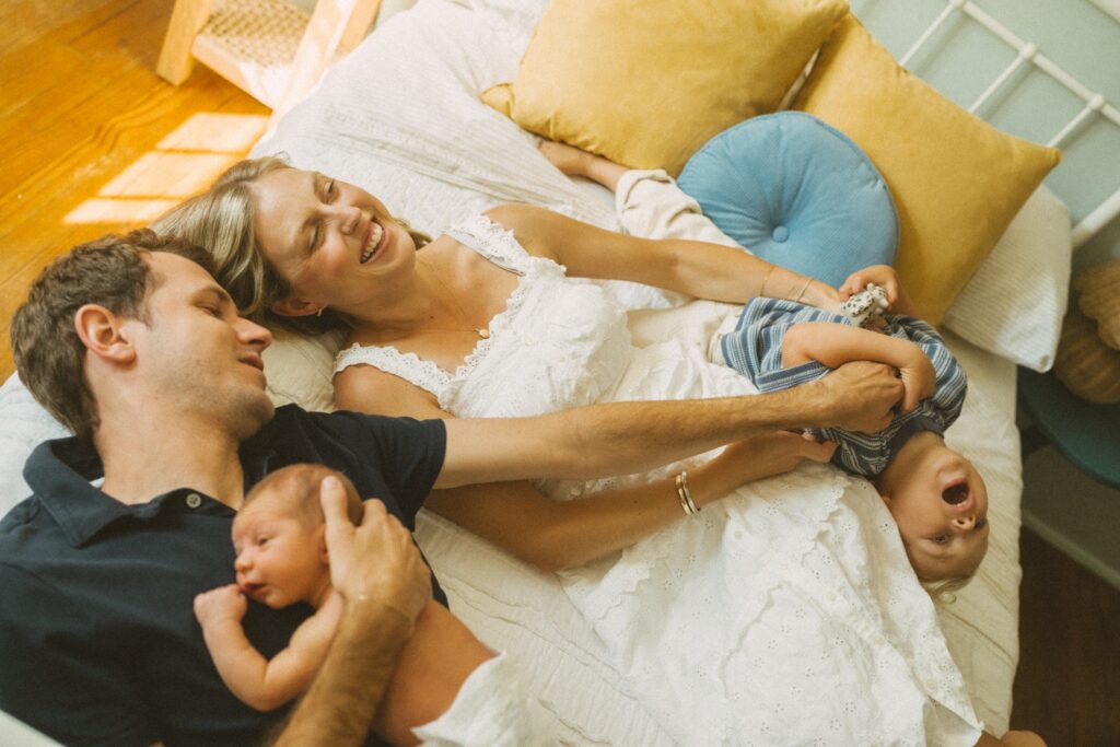 family laughing while laying on the bed during their lifestyle photography session in cincinnati