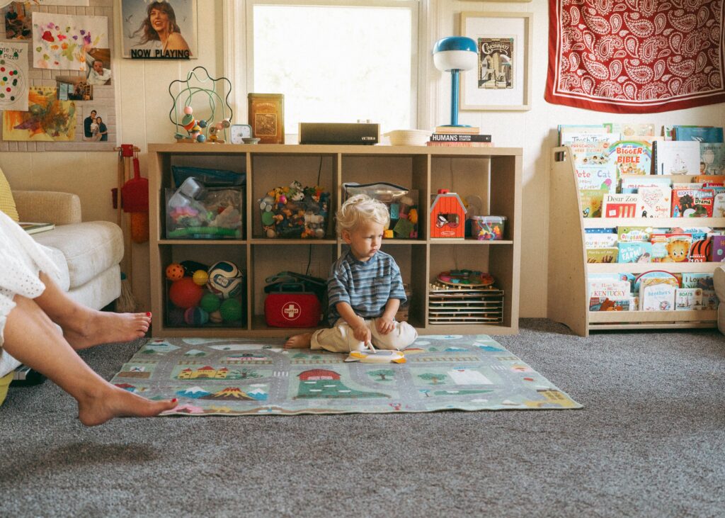 Toddler sitting on the ground in front of his bookcase during a lifestyle family session in cincinnati.