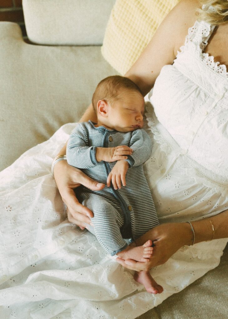 newborn boy laying in his mother's lap asleep during their lifestyle session with cincinnati photographer