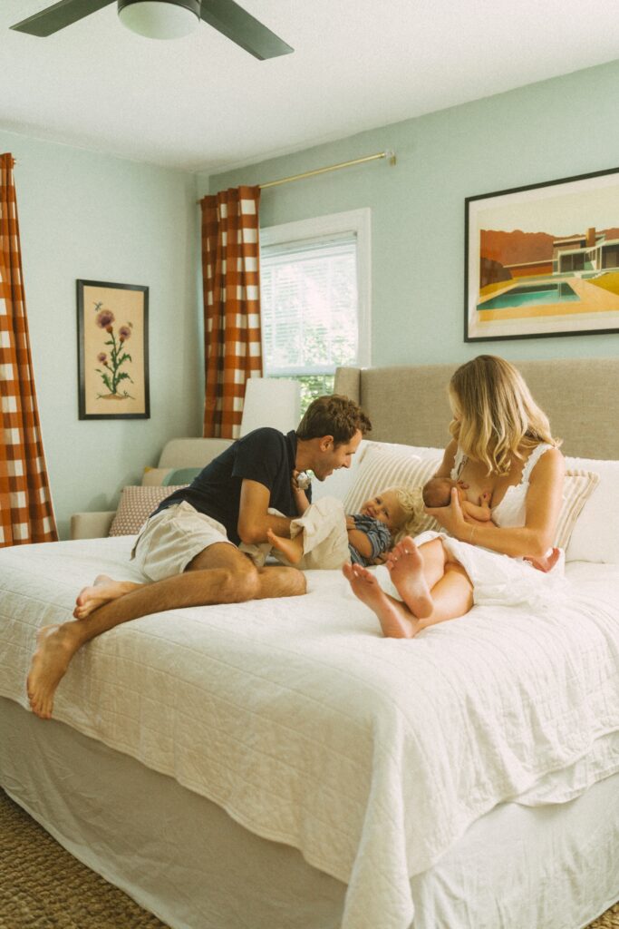 family hanging out on the bed while mom nurses newborn baby