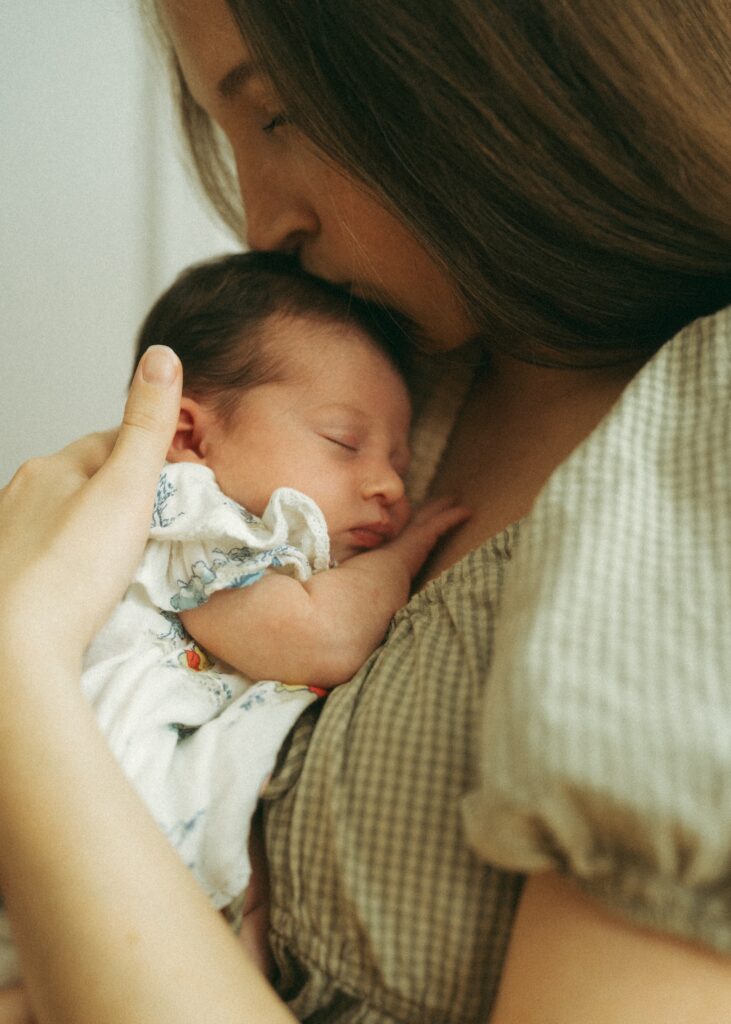 mom kissing her newborn baby's head while sleeping